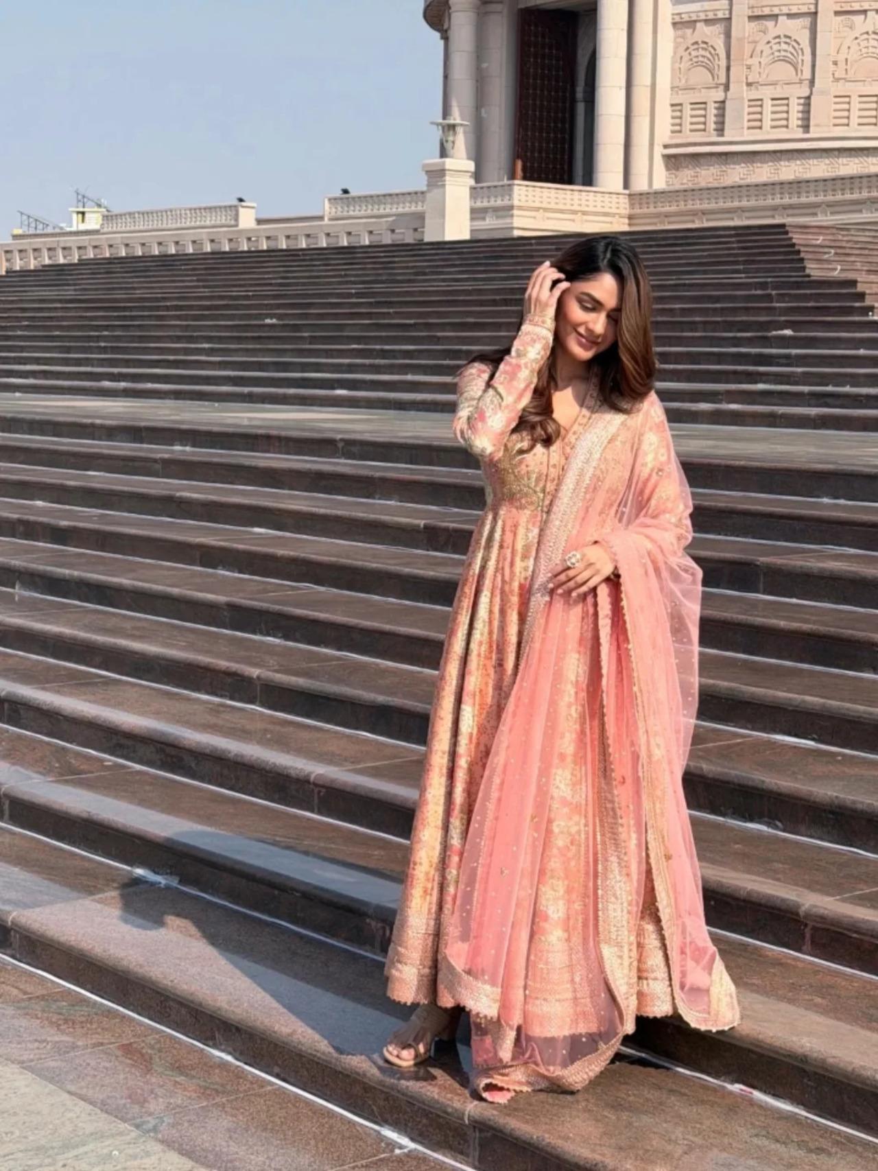 Mrunal Thakur looks graceful in a peach and gold embroidered anarkali set paired with a matching dupatta. The delicate detailing add a regal charm to her look.